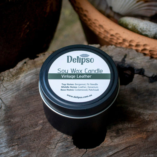 Delipso soy wax candle labeled 'Vintage Leather' on a wooden surface with natural elements.